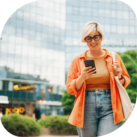 Mulher sorrindo com o telefone em mãos utilizando o Super App